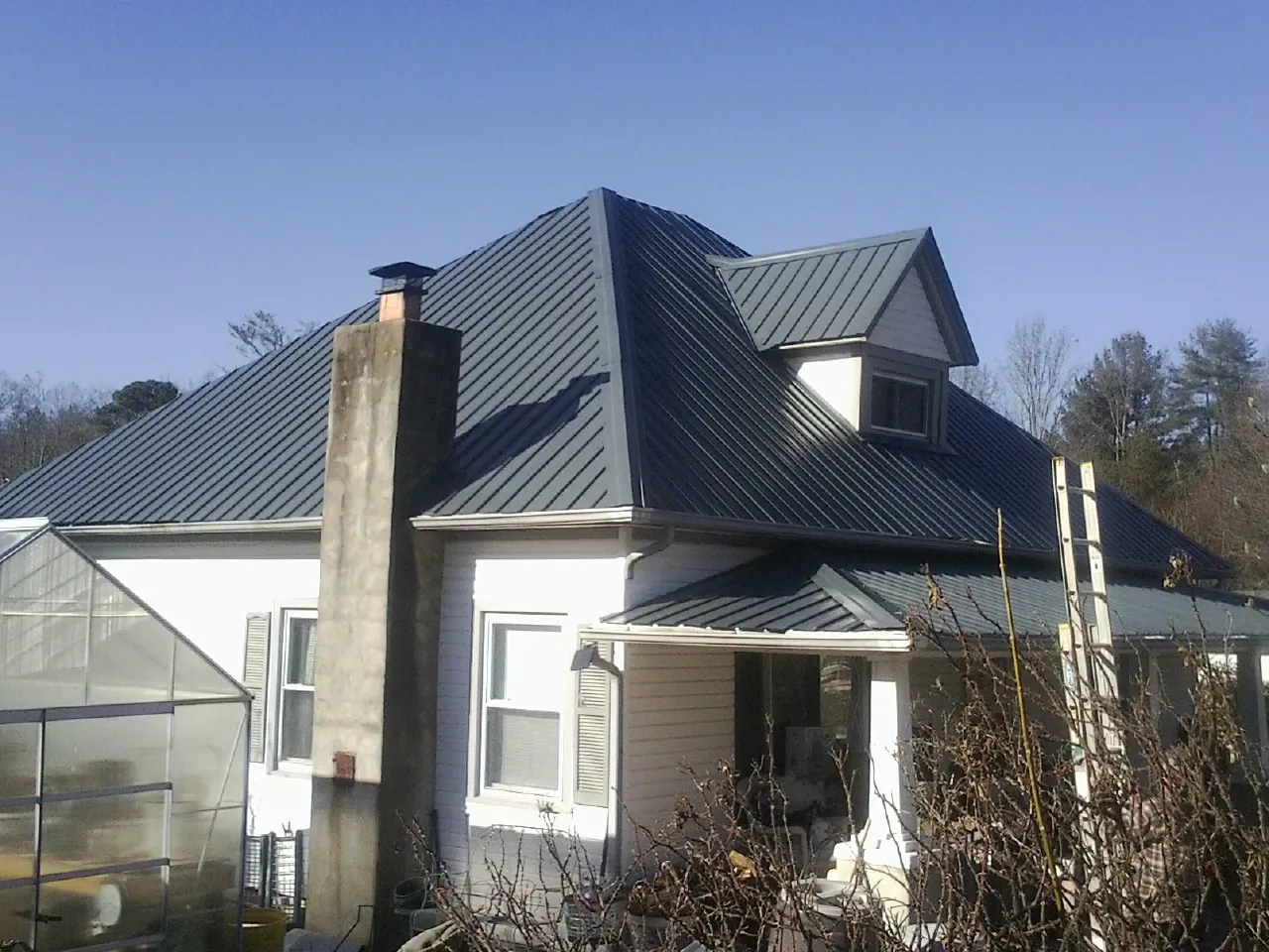 Dark blue standing seam metal roof on a white farmhouse with dormer — Slate & Tile Roof Repair by Roofing Brothers in South Grafton