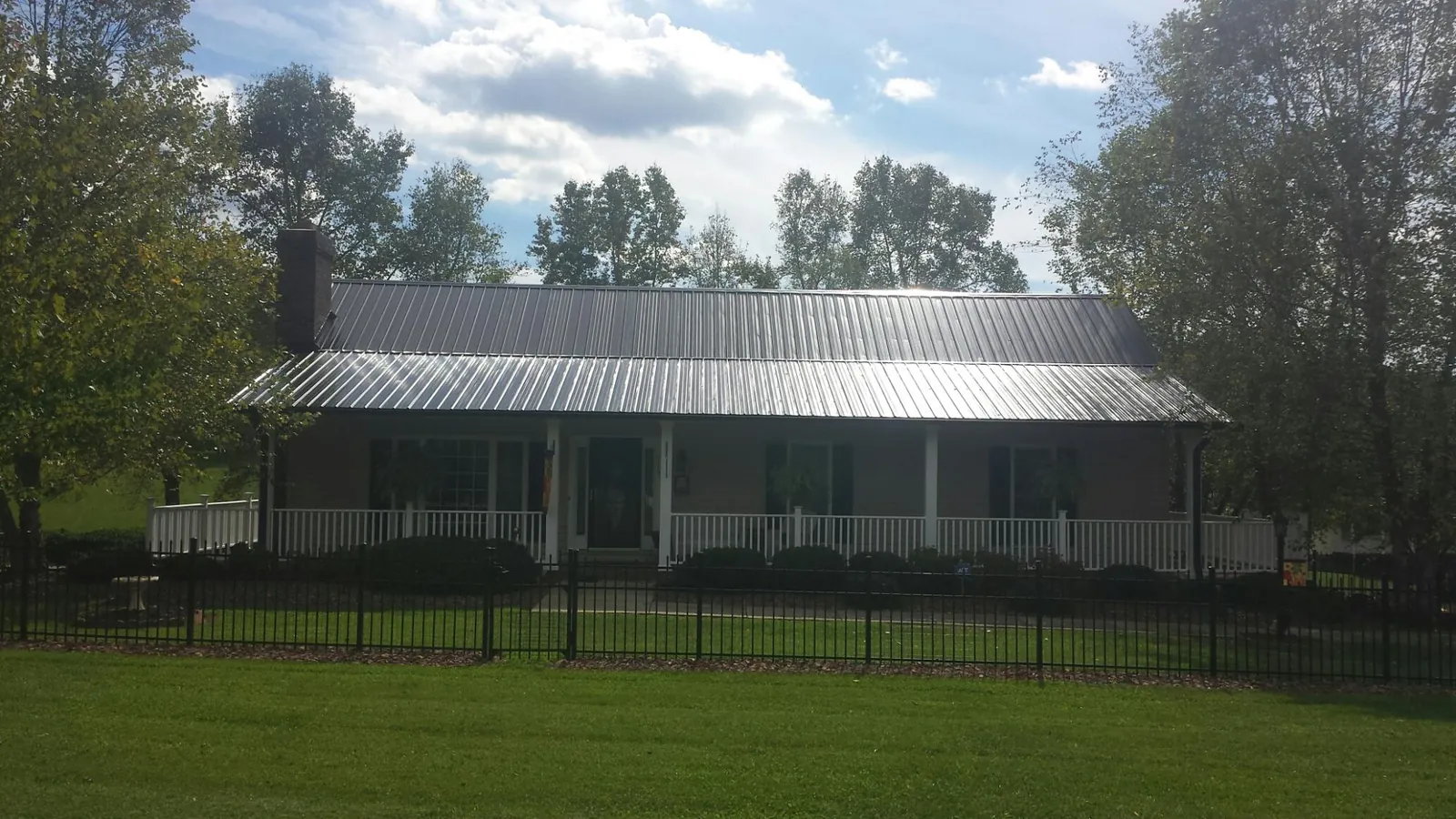 Gray metal roof on a brick ranch with a full width front porch — Gutter Guard Installation work by our crew in South Grafton