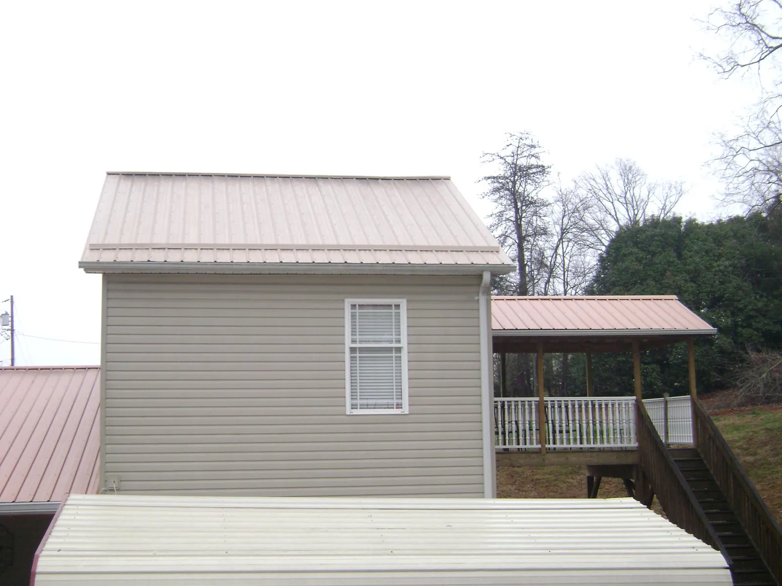 Tan metal roofs on a two story addition and attached porch, from a Roof Replacement job in South Grafton