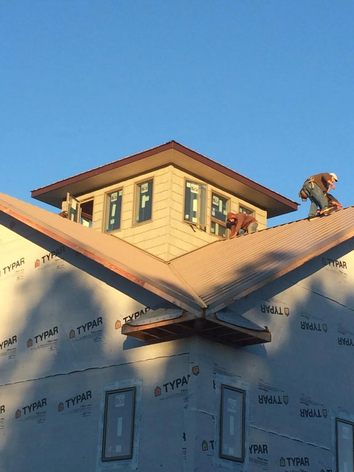 Roofers working around a rooftop cupola on a new metal roof at sunset — Roof Waterproofing in South Grafton by Roofing Brothers